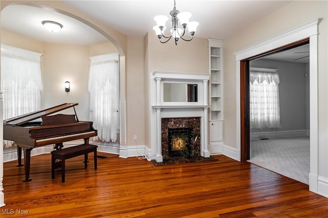 interior space with built in shelves, a chandelier, a fireplace, and wood-type flooring