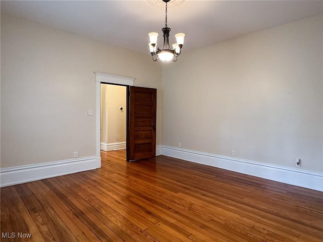 empty room with hardwood / wood-style flooring and a chandelier