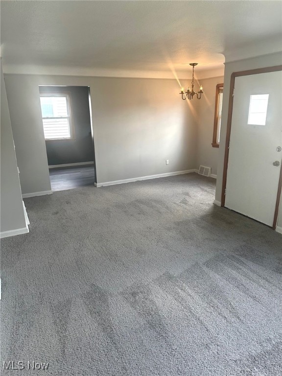 spare room featuring a chandelier and carpet flooring