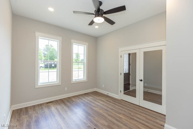 empty room with ceiling fan, dark hardwood / wood-style flooring, and french doors