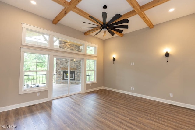 unfurnished room with plenty of natural light, dark hardwood / wood-style floors, beam ceiling, and ceiling fan