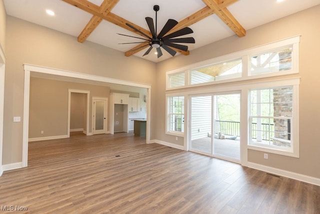 unfurnished living room with beam ceiling, dark hardwood / wood-style floors, and ceiling fan