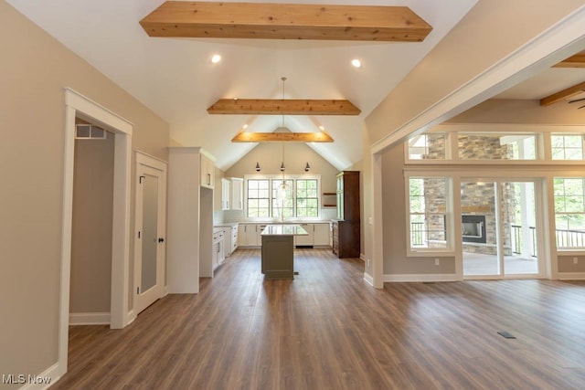 kitchen with white cabinets, vaulted ceiling with beams, a kitchen island, and dark wood-type flooring