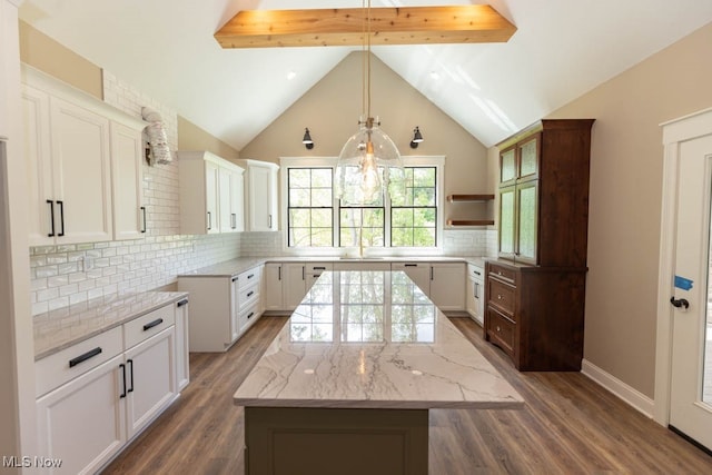 kitchen with backsplash, white cabinetry, a kitchen island, and dark hardwood / wood-style floors