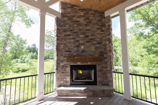 wooden terrace featuring an outdoor stone fireplace