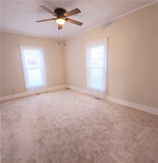 carpeted spare room featuring crown molding, plenty of natural light, and ceiling fan