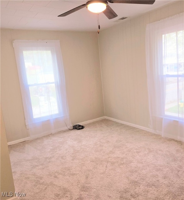 spare room featuring ceiling fan, carpet flooring, and plenty of natural light