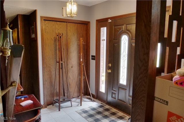 tiled entrance foyer featuring a notable chandelier