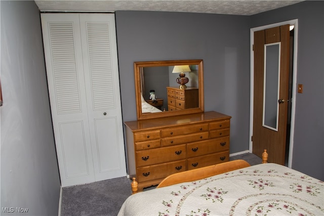 bedroom with a textured ceiling, dark carpet, and a closet