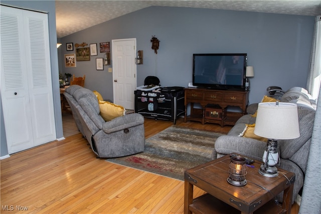 living room with a textured ceiling, hardwood / wood-style flooring, and vaulted ceiling