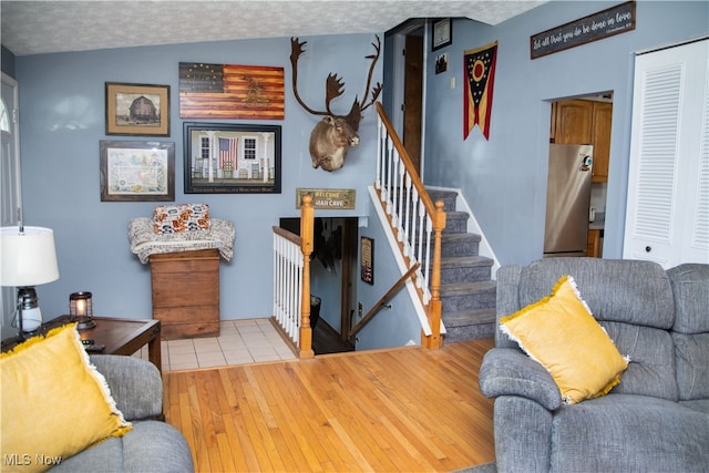 living room featuring lofted ceiling, light hardwood / wood-style flooring, and a textured ceiling