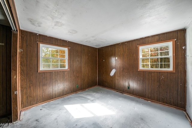 unfurnished room featuring wooden walls