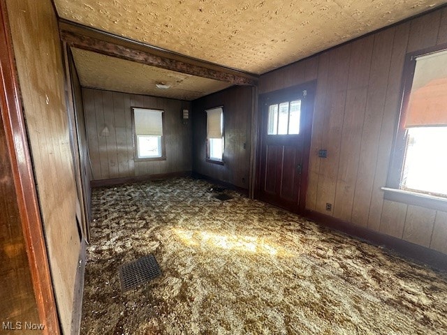 carpeted entrance foyer with wood walls