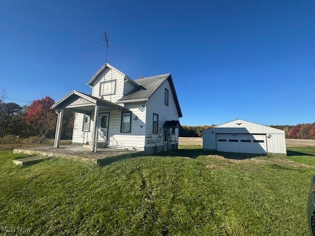 view of front facade featuring a front yard, a garage, and an outbuilding