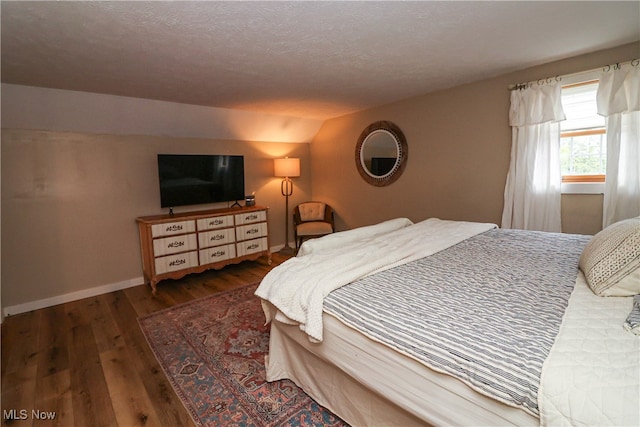 bedroom featuring lofted ceiling, a textured ceiling, and dark hardwood / wood-style floors