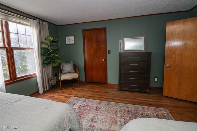 bedroom with dark wood-type flooring, a textured ceiling, and ornamental molding