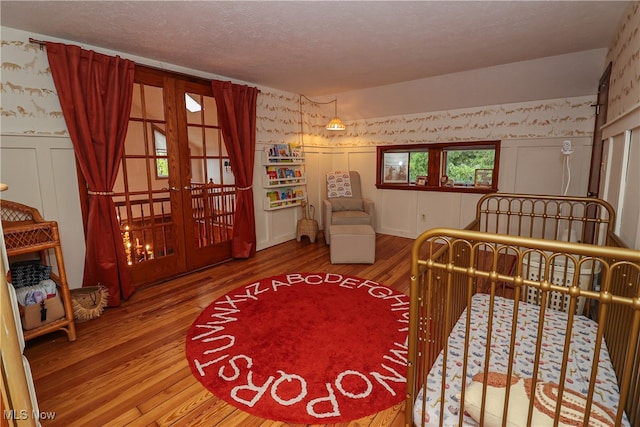 bedroom with french doors, wood-type flooring, and a textured ceiling