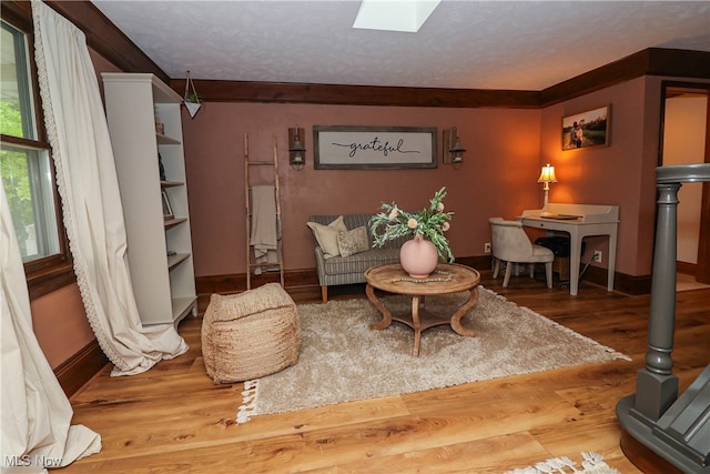 sitting room featuring ornamental molding, hardwood / wood-style flooring, and a skylight