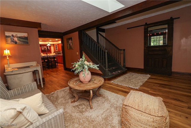 living room with a barn door and hardwood / wood-style flooring