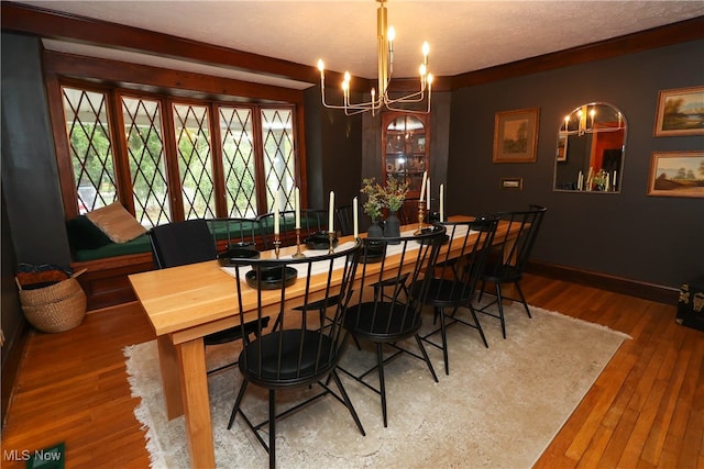 dining space with an inviting chandelier, a textured ceiling, and hardwood / wood-style flooring