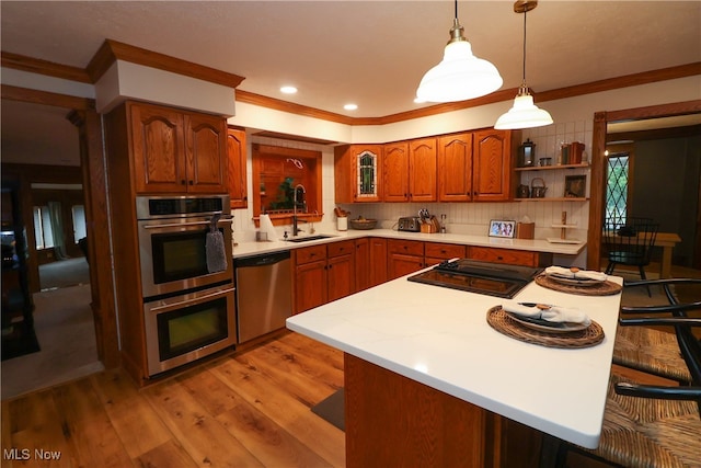 kitchen with hanging light fixtures, a breakfast bar, light hardwood / wood-style flooring, sink, and stainless steel appliances