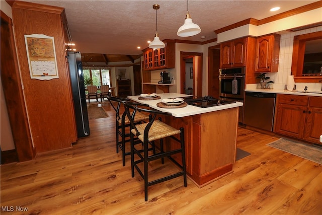 kitchen featuring appliances with stainless steel finishes, light hardwood / wood-style flooring, a textured ceiling, and a center island