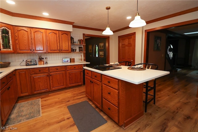 kitchen with decorative backsplash, a breakfast bar area, hanging light fixtures, a center island, and light wood-type flooring