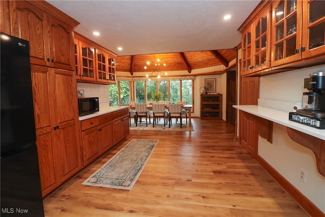 kitchen featuring vaulted ceiling with beams, light hardwood / wood-style flooring, black appliances, a chandelier, and a textured ceiling