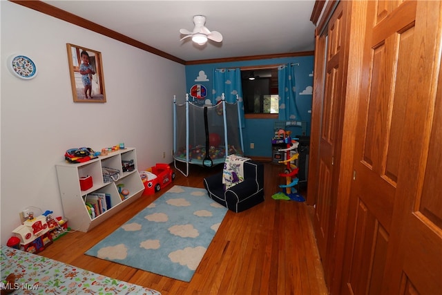 game room featuring hardwood / wood-style floors, crown molding, and ceiling fan