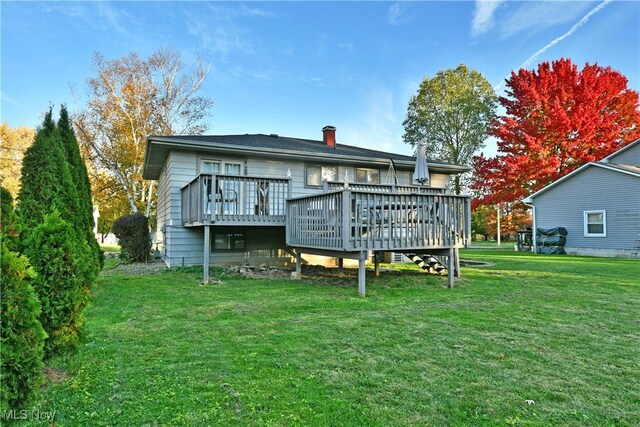 rear view of property featuring a yard and a wooden deck