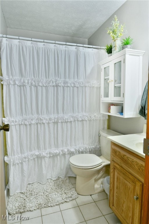 bathroom with walk in shower, tile patterned flooring, a textured ceiling, toilet, and vanity