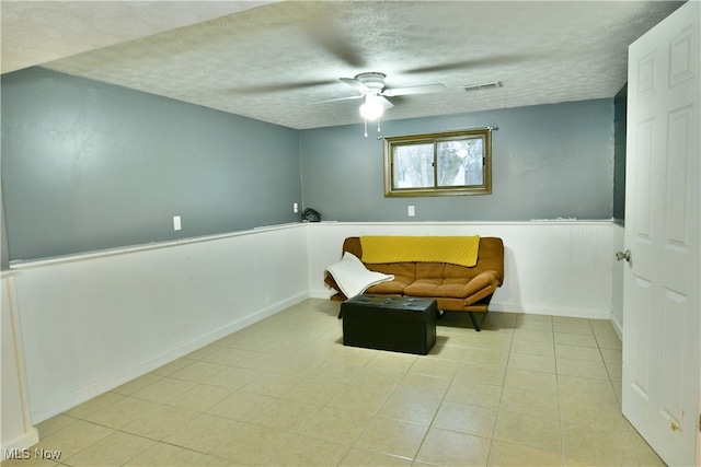 living area with a textured ceiling and ceiling fan