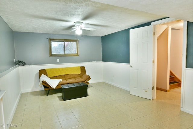 sitting room with ceiling fan, light tile patterned floors, and a textured ceiling