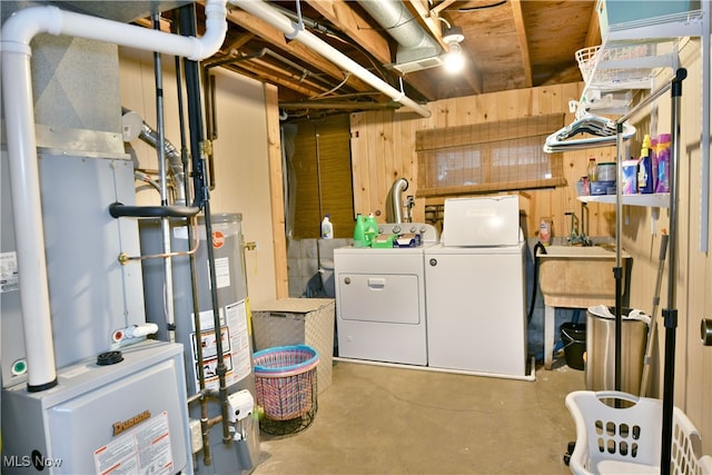 basement with separate washer and dryer, water heater, and wooden walls