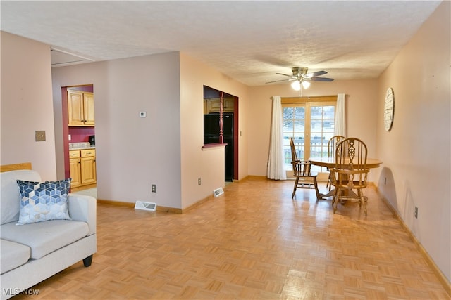 living room with a textured ceiling, light parquet flooring, and ceiling fan