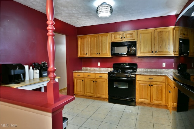 kitchen featuring light tile patterned flooring, black appliances, and a textured ceiling