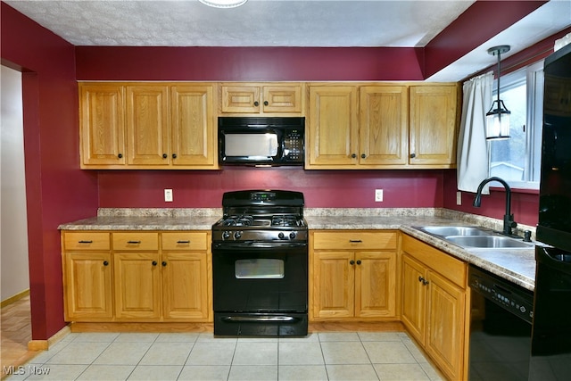 kitchen featuring sink, light tile patterned floors, black appliances, and decorative light fixtures