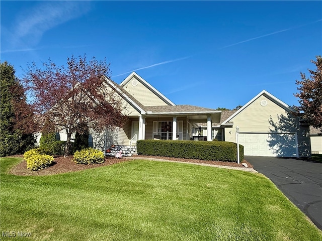 view of front of home with covered porch, a front yard, and a garage