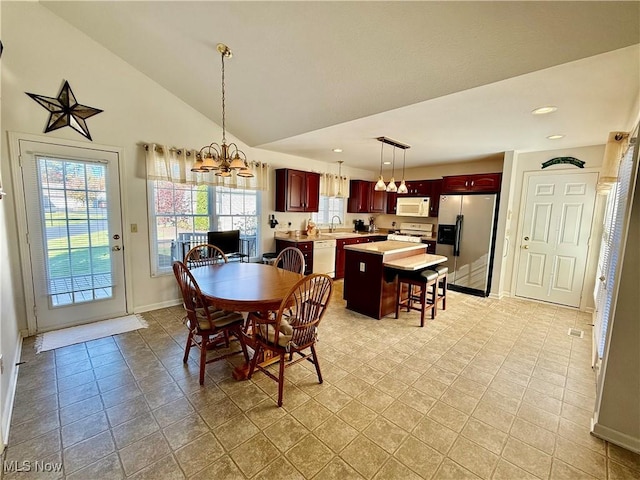 tiled dining area featuring an inviting chandelier, vaulted ceiling, and sink