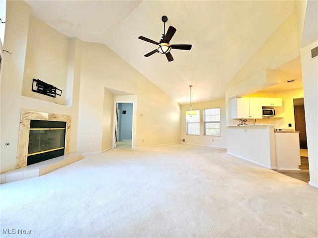 unfurnished living room featuring ceiling fan, high vaulted ceiling, a premium fireplace, and light carpet