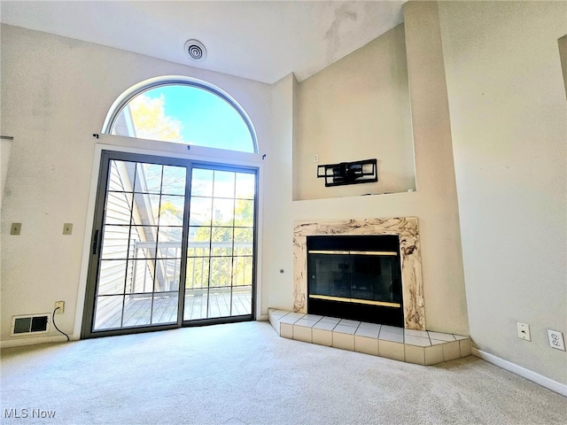 unfurnished living room with carpet, a high ceiling, and a fireplace