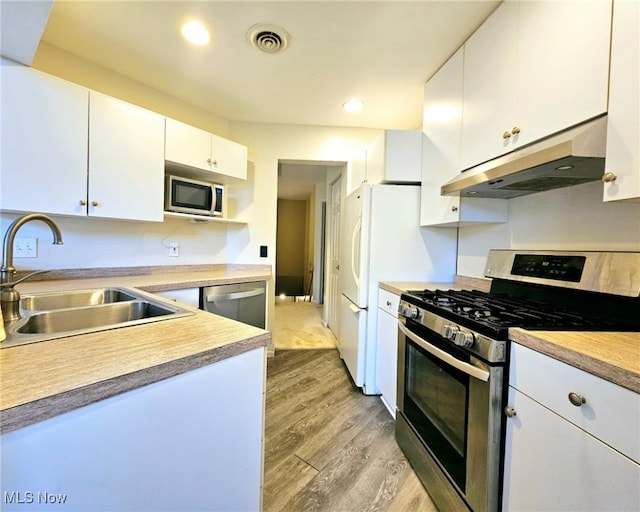 kitchen featuring white cabinetry, appliances with stainless steel finishes, sink, and light wood-type flooring