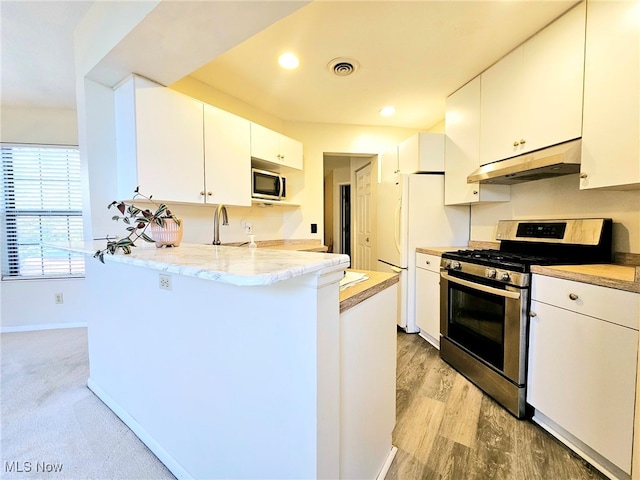 kitchen with appliances with stainless steel finishes, light hardwood / wood-style flooring, white cabinets, and kitchen peninsula