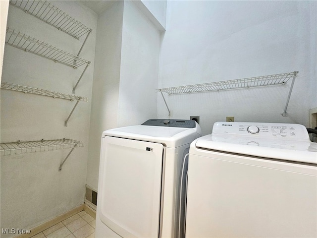 clothes washing area with light tile patterned flooring and separate washer and dryer