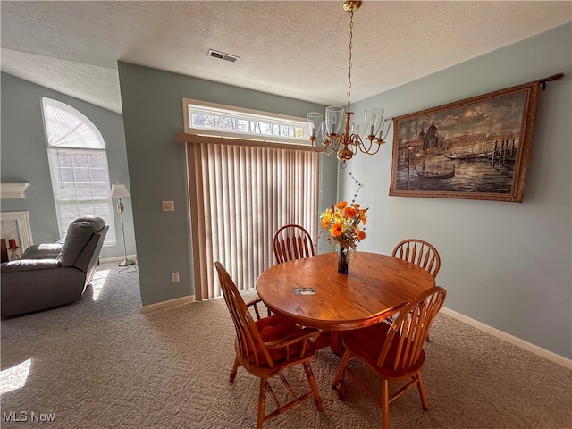 carpeted dining space with a textured ceiling, a chandelier, and plenty of natural light