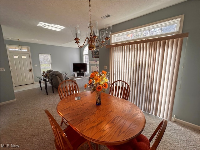 carpeted dining room with an inviting chandelier, a textured ceiling, and plenty of natural light