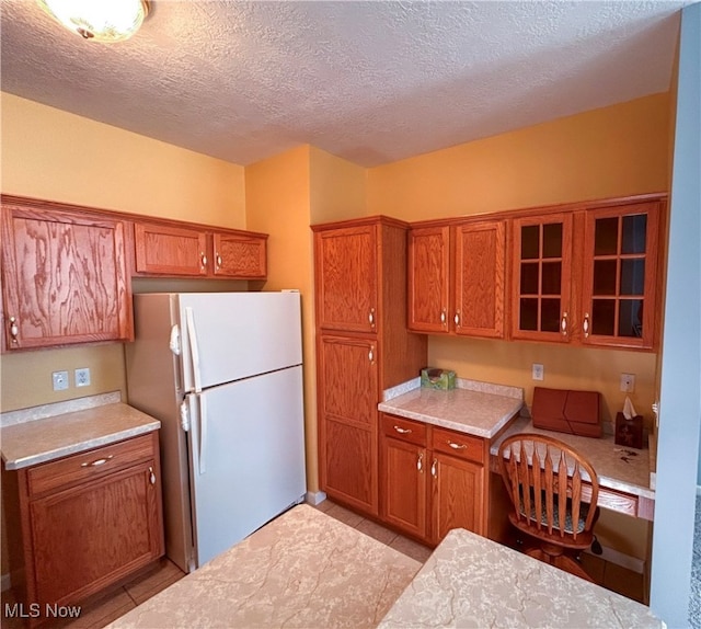 kitchen with a textured ceiling, light tile patterned flooring, and white refrigerator