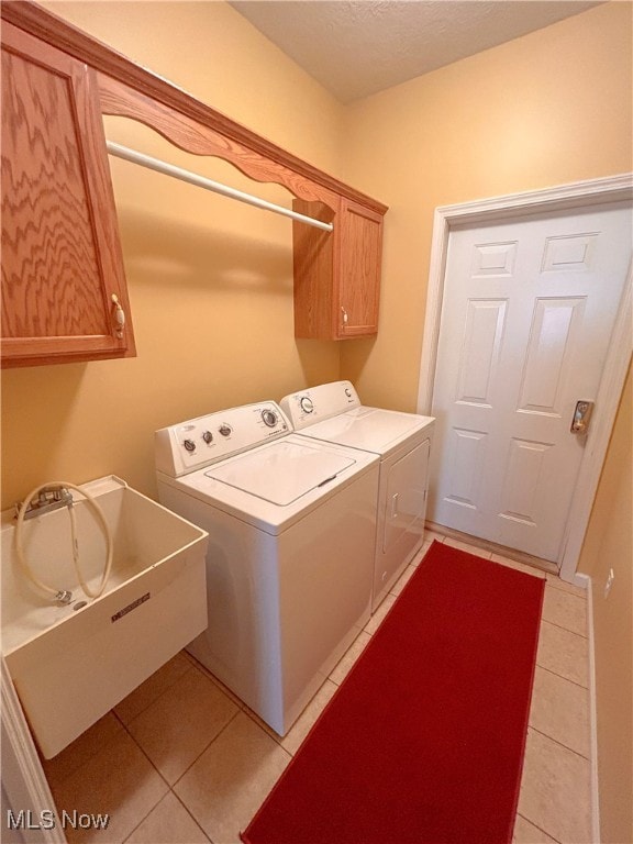 laundry room featuring cabinets, independent washer and dryer, sink, and light tile patterned flooring