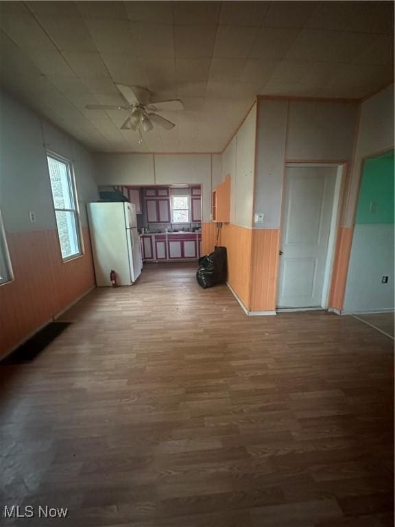 spare room with hardwood / wood-style flooring, wooden walls, and ceiling fan