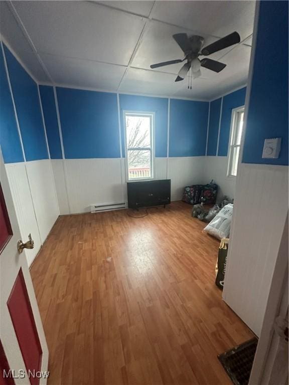 interior space featuring ceiling fan, a baseboard radiator, plenty of natural light, and wood-type flooring